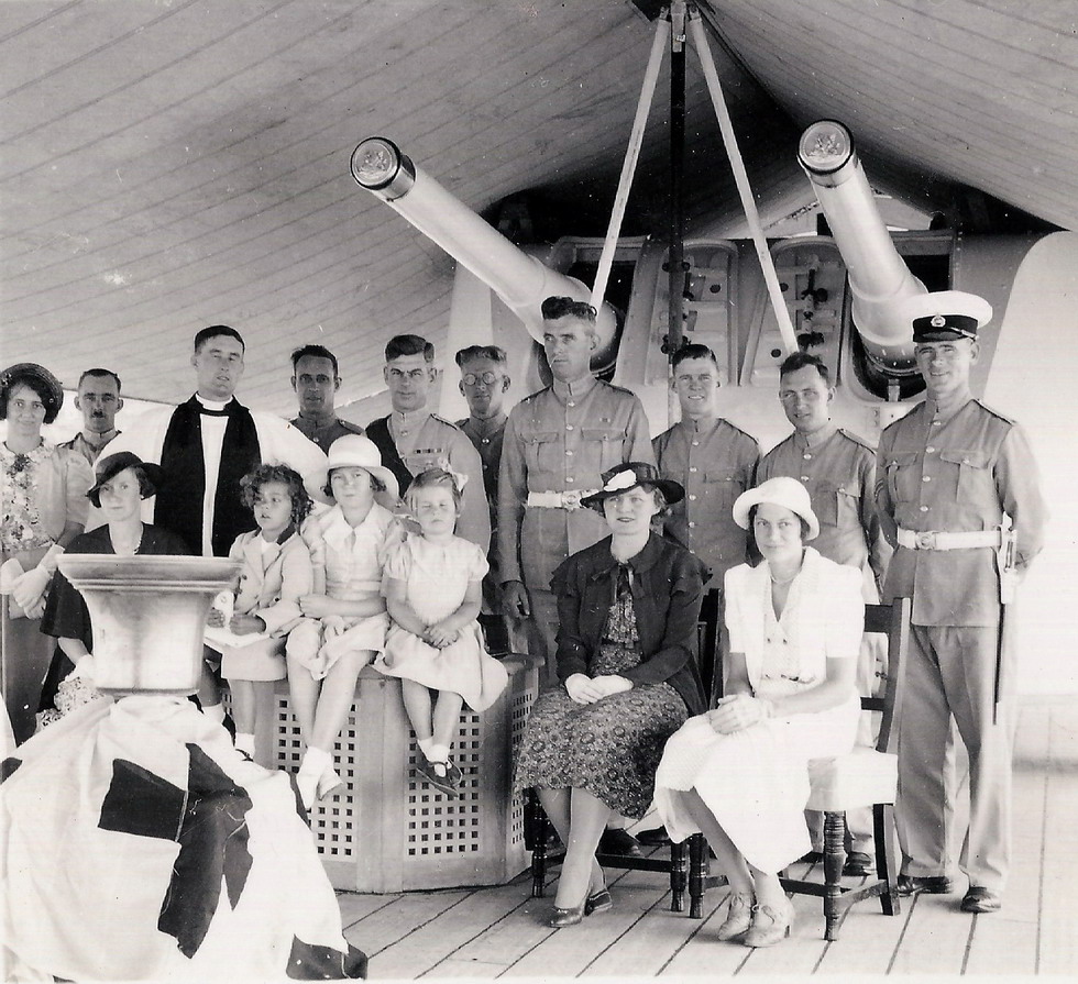 In the centre is John's father, Colour Sergeant Norman Dallen, Sergeant Major of the Garrison in his distinctive red sash.\n The curly little girl sitting up on the bollard cover in front of the Chaplain is John's five year old sister Norma. The tall Marine just to the right is Gerry Saunders and his wife is the lady in the pretty white dress.