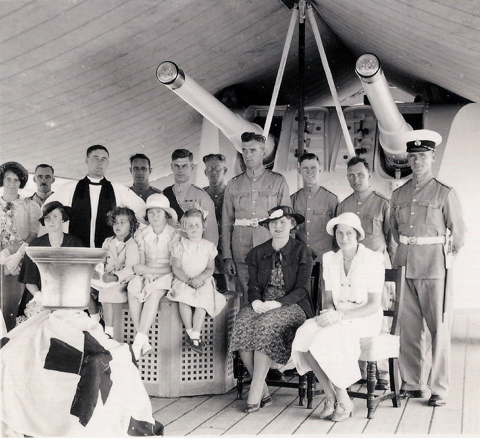 In the centre is John's father, Colour Sergeant Norman Dallen, Sergeant Major of the Garrison in his distinctive red sash.\n The curly little girl sitting up on the bollard cover in front of the Chaplain is John's five year old sister Norma. The tall Marine just to the right is Gerry Saunders and his wife is the lady in the pretty white dress.