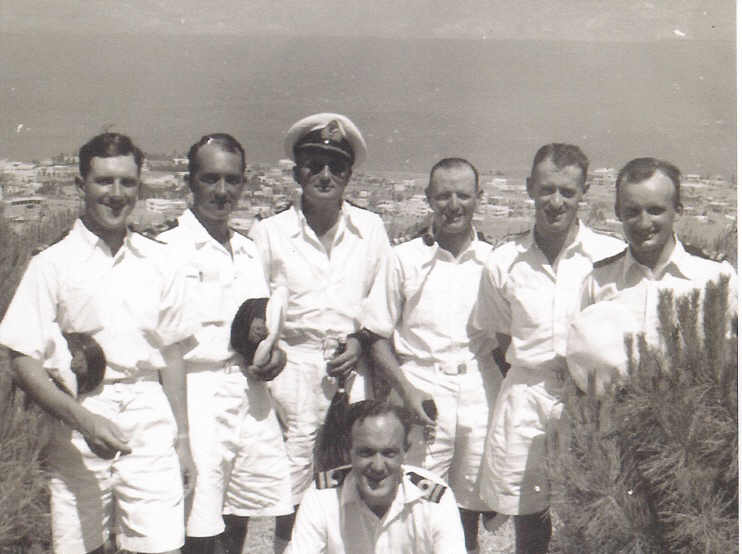 This depicts a group of officers at Tiberias by the Sea of Galilee in August 1941. They are Lieut Frank Woodward, Lieut Donald Wilson, Surg Cdr Thomas Larkworthy, Cdr Philip Berry (with the pipe), Pay Lieut Bruce Thomson and Lieut James Knowles. The Lieutenant on ground has not been identified yet.\n